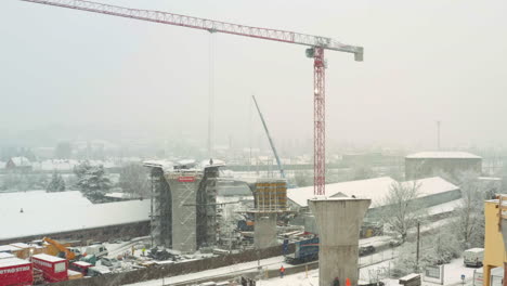 Tower-crane-moving-in-snowstorm-at-highway-bridge-construction-site