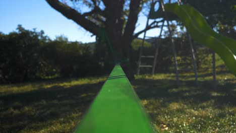 Close-up-On-A-green-Slack-Line-In-A-Sunny-Children's-Garden-with-a-moving-focus-point-in-france