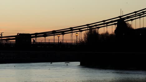 Silhouette-Von-Pendlern,-Die-Bei-Sonnenaufgang-Die-Hammersmith-Bridge-überqueren
