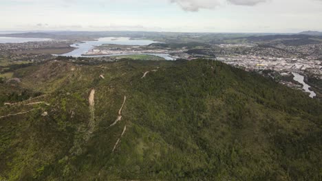 Aerial-view-of-forested-Mount-Parihaka-and-Whangarei-cityscape,-New-Zealand