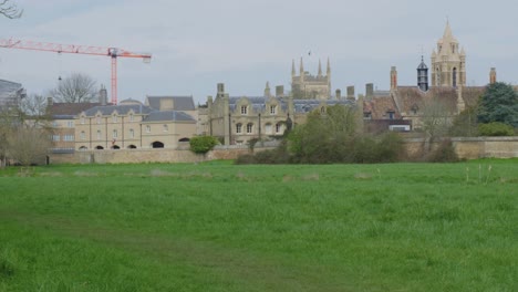 Grassy-field-fronts-construction-cranes-and-classic-English-architecture,-England