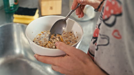 Una-Mujer-En-Pijama-Cómodo-Comienza-Su-Día-Con-Una-Nota-Saludable,-Preparando-Un-Delicioso-Cereal,-Muesli-Desayuno