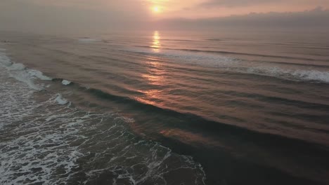 Establishing-aerial-shot-of-big-waves-in-ocean,-perfect-color-sunrise-in-Brazilian-beach