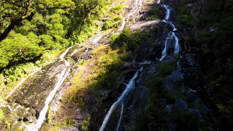 Small-Waterfall-Cascading-Down-Mountainside---tilt-up-wide-shot