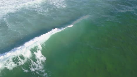 Drone-flight-following-a-surfer-on-waves-in-Cascais,-europe