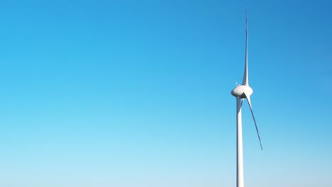 Spinning-Blades-of-Single-Wind-Turbine-Against-Blue-Sky-With-Text-Space