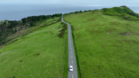 Car-driving-on-Spanish-road-away-from-ocean,-aerial-drone-view
