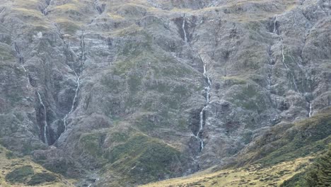 Numerous-narrow-waterfalls-running-down-rugged-cliff