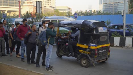 Indian-corporate-people-standing-in-queue-to-take-autorickshaws-for-commuting-after-office-hour-ends,-Mumbai