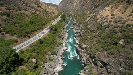 Scenic-route-beside-Kawarau-River-and-canyon,-Road-trip-scenery-of-New-Zealand---drone