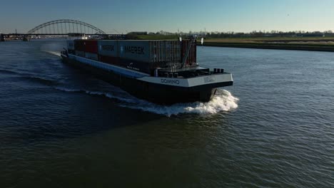 Container-ship-Domino-navigating-through-the-wide-canal-of-Alblasserdam,-aerial-view