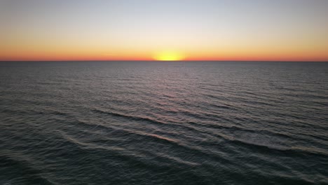 Der-Sonnenuntergang-Schafft-Eine-Wunderschöne-Landschaft,-In-Der-Der-Purpurrote-Himmel-Mit-Dem-Hintergrund-Des-Wassers-Und-Den-Vom-Strand-Aus-Sichtbaren-Sanften-Wellen-Verschmilzt