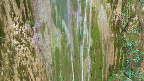 Aufsteigende-Drohne-Schoss-An-Einem-Sonnigen-Tag-Entlang-Einer-Moosigen-Felswand-Mit-Tosendem-Wasserfall---Salto-Del-Limon,-Samana,-Dominikanische-Republik