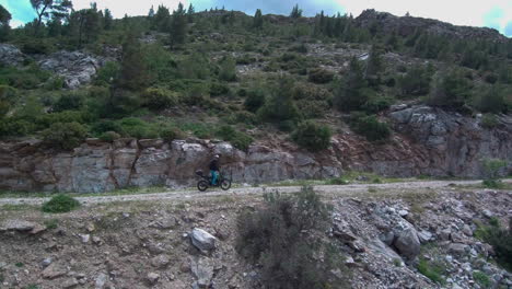 Motorcyclist-riding-off-road-standing-up-on-his-bike-on-a-gravel-mountain-road