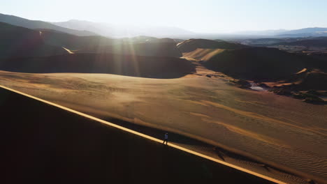Luftaufnahme,-Die-Eine-Person-Auf-Einer-Sanddüne-In-Der-Namib-Wüste-Zeigt,-Sonnenuntergang-In-Namibia-–-Umgekehrt,-Geneigt,-Drohnenaufnahme