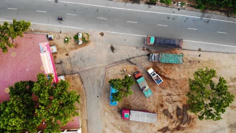 Birdseye-view-of-truck-parking-at-a-rest-stop-in-the-outskirts-of-Vellore,-India-near-a-road