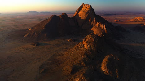 Aerial-view-of-rocky-mountains-and-endless-wasteland-in-the-Namib-desert,-sunny-evening-in-Namibia
