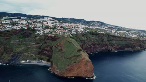 Aerial-view-rising-up-towards-Ponta-du-Garajau-green-island-coastline,-Madeira,-Portugal