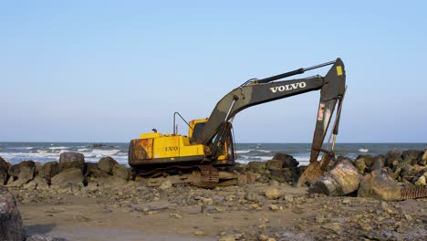 Abandoned-Yellow-Digger-Machinery-on-Rocky-Beach-Thailand