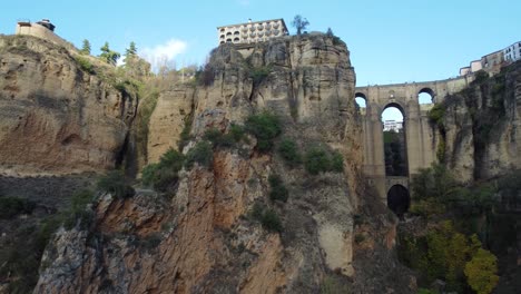 Landmark-arch-bridge-of-Ronda-city-with-buildings-on-top-of-cliff,-aerial-view