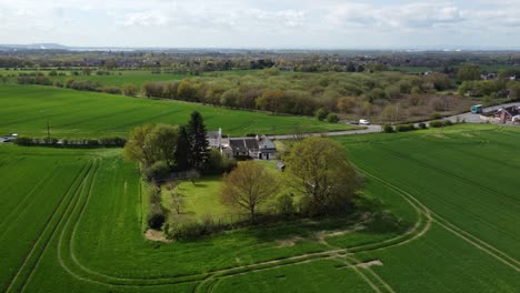Rural-Cheshire-farmhouse-aerial-view-surrounded-by-lush-green-trees-and-agricultural-farmland-countryside-fields