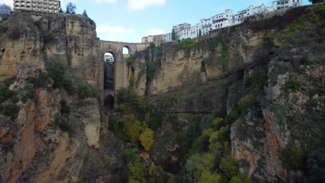 Famous-Ronda-city-bridge-and-buildings-on-top-of-cliff,-aerial-drone-view