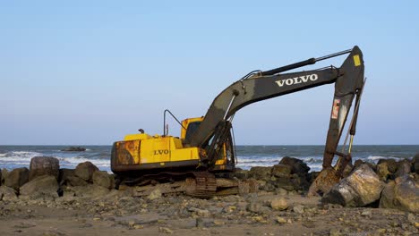 Verlassener-Gelber-Bagger-An-Einem-Felsigen-Strand-In-Thailand