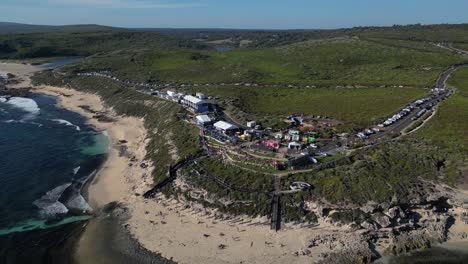 Drone-shot-of-famous-Margaret-River-Pro-2023-Surf-Championship-in-Western-Australia-during-sunny-day---People-resting-on-sandy-beach-in-front-of-ocean