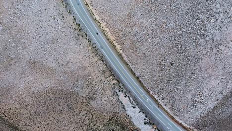 Overhead-view-of-a-car-driving-along-a-highway-in-the-Salta-Province,-Argentina,-Drone-overhead-orbit