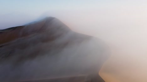 Drone-shot-of-sand-dunes-covered-in-thick-fog,-sunrise-at-the-Namib-desert,-in-Namibia