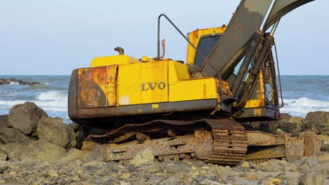Abandoned-Yellow-Digger-on-Rocky-Beach-in-Thailand