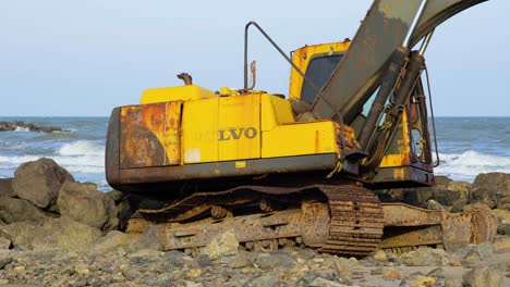 Verlassener-Gelber-Bagger-Am-Felsigen-Strand-In-Thailand