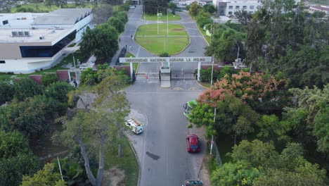 Drone-flying-above-the-entrance-to-the-National-Agrarian-University,-in-Spanish,-Universidad-Nacional-Agraria