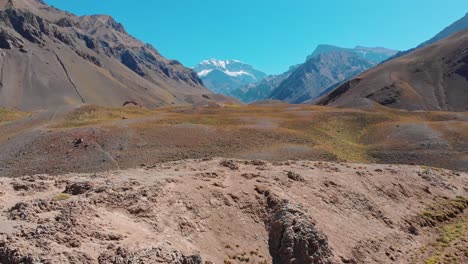 Aerial-through-the-arid-valleys-in-the-Andes-with-Mount-Aconcagua,-highest-in-the-Americas,-in-the-background,-Mendoza-Province,-Argentina