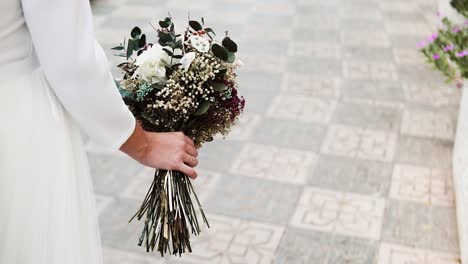 Elegant-bride-walking-in-the-street-holding-a-beautiful-bouquet-of-flowers