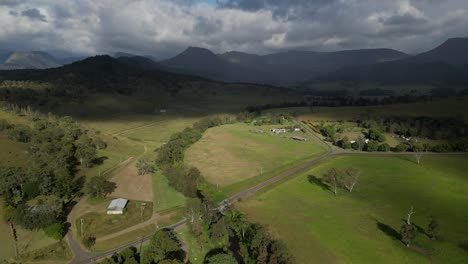 Aerial-views-over-farmland-in-Lamington-in-the-Scenic-Rim-with-rain-fall-in-the-distance,-Queensland,-Australia