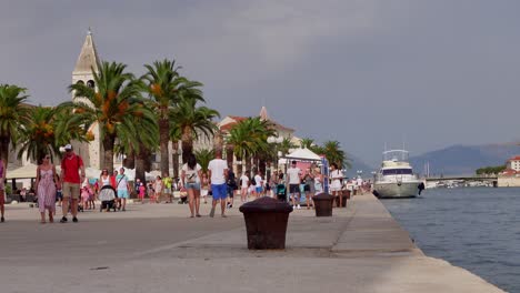 A-static-shot-presents-tourists-walking-on-the-marina-in-Trogir,-Croatia,-on-a-sunny-and-cloudy-day