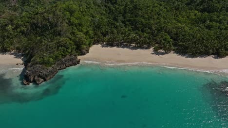 White-beach-between-turquoise-waters-and-lush-forest,-Playa-Rincon-beach-at-Las-Galeras,-Samana-in-Dominican-Republic