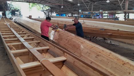 Los-Artesanos-Utilizan-Una-Herramienta-De-Pulido-Para-El-Casco-Del-Barco-Dragón-En-Una-Fábrica-De-Barcos.