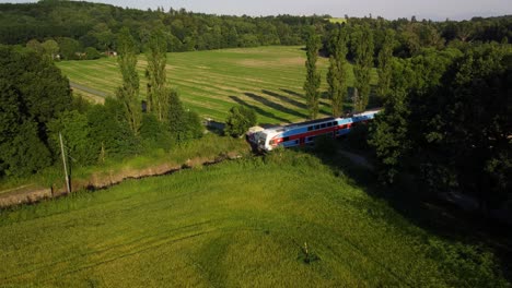 Aerial-video-of-a-local-train-passing-by,-driving-through-beautiful-Czech-countryside