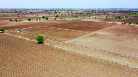 Cámara-Aérea-Moviéndose-Hacia-Atrás-De-Una-Máquina-Excavadora-En-Una-Granja-Para-El-Plan-Subterráneo-Del-Sistema-De-Agua