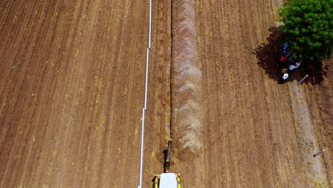 Aerial-overhead-shot-of-excavation-working-and-digging-for-water-pipeline-at-agricultural-farm