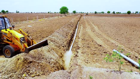 Erdbewegungsmaschine-Vertuscht-Wasserleitung-Mit-Erde,-Schwere-Baggermaschine-Auf-Indischen-Agrarflächen