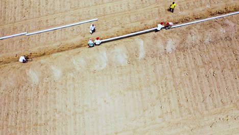 Aerial-camera-moving-forwards-and-rotted-shot-of-Indian-labor-and-farmer-doing-feting’s-of-water-pipeline-at-farm-land