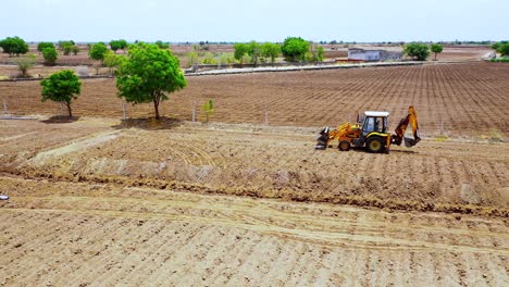 Aerial-Cinematic-shot-of-following-heavy-duty-excavation-machine-at-Indian-agricultural-land