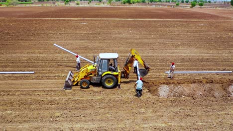 Indischer-Bauer-Trägt-Eine-Wasserleitung-Für-Die-Armaturen-Auf-Landwirtschaftlichen-Flächen,-Luftaufnahme-Von-Oben-Nach-Unten