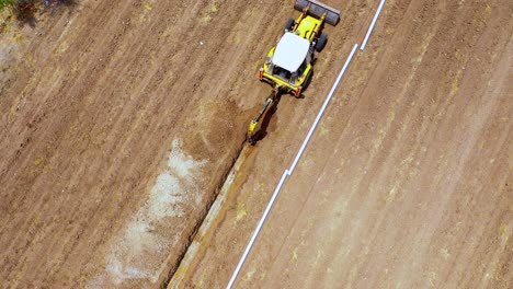 Cámara-Aérea-Acercándose-A-Una-Excavación-Excavando-Suelo-Leído,-Accesorios-De-Tuberías-De-Agua-Para-Las-Temporadas-De-Verano