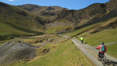 Cyclists-on-gravel-track-leading-to-abandoned-industrial-mine-at-Force-Crag-Mine-Coledale-Beck-in-the-English-Lake-District