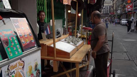 Local-seafood-vendors-display-oysters,-prepare-for-business,-and-await-customers-at-the-famous-Yaowarat-Chinatown,-Bangkok,-Thailand