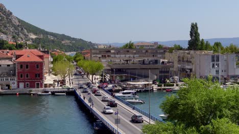 Static-shot-of-a-bridge-over-the-Cetina-River-in-Omis,-Croatia,-featuring-cars-and-pedestrians